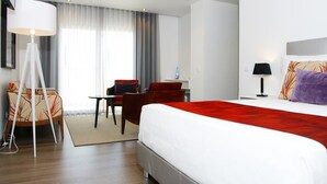 A modern hotel room with a large bed, a desk, a chair, and a lamp. - Hotel Concha (Alcobaça)