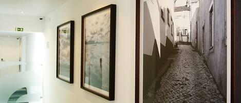 A hallway with framed artworks and a staircase leading to an upper level.