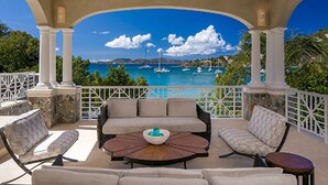 Un espacio de estar al aire libre con techo y vistas al mar y barcos.