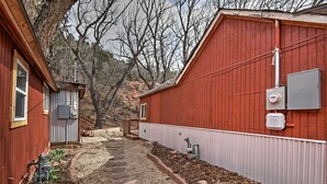 Un sendero estrecho que lleva a un edificio rojo con una cerca metálica y un cobertizo pequeño.