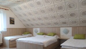 A bedroom with three beds, a wooden headboard, and a geometric ceiling design. - Apartmány OKOUN (Velke Losiny)