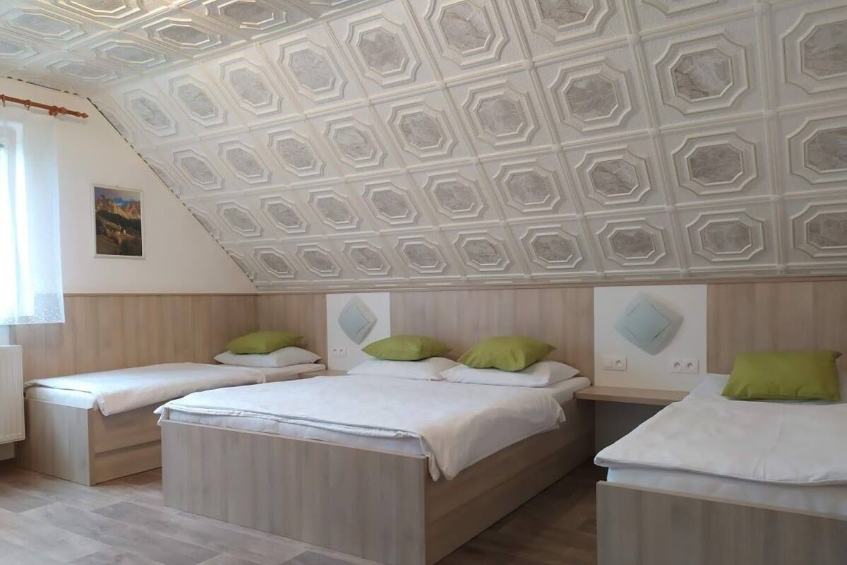 A bedroom with three beds, a wooden headboard, and a geometric ceiling design.