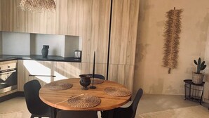A modern kitchen with a wooden dining table, black chairs, and a hanging light fixture. - Spacious, light & cozy apartments with ocean views (Santiago del Teide)