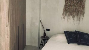A bedroom with a bed, pillows, a small table with a bottle, and a woven wall hanging. - Spacious, light & cozy apartments with ocean views (Santiago del Teide)