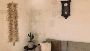 A room with a textured wall, a cacti plant on a small table, a dark wooden clock on the wall, and a beige sofa. - Spacious, light & cozy apartments with ocean views (Santiago del Teide)