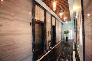 A hallway with marble flooring, wooden ceiling panels, and a potted plant. - Shanghai Jinshanzui Yucun Hotel (Shanghai)