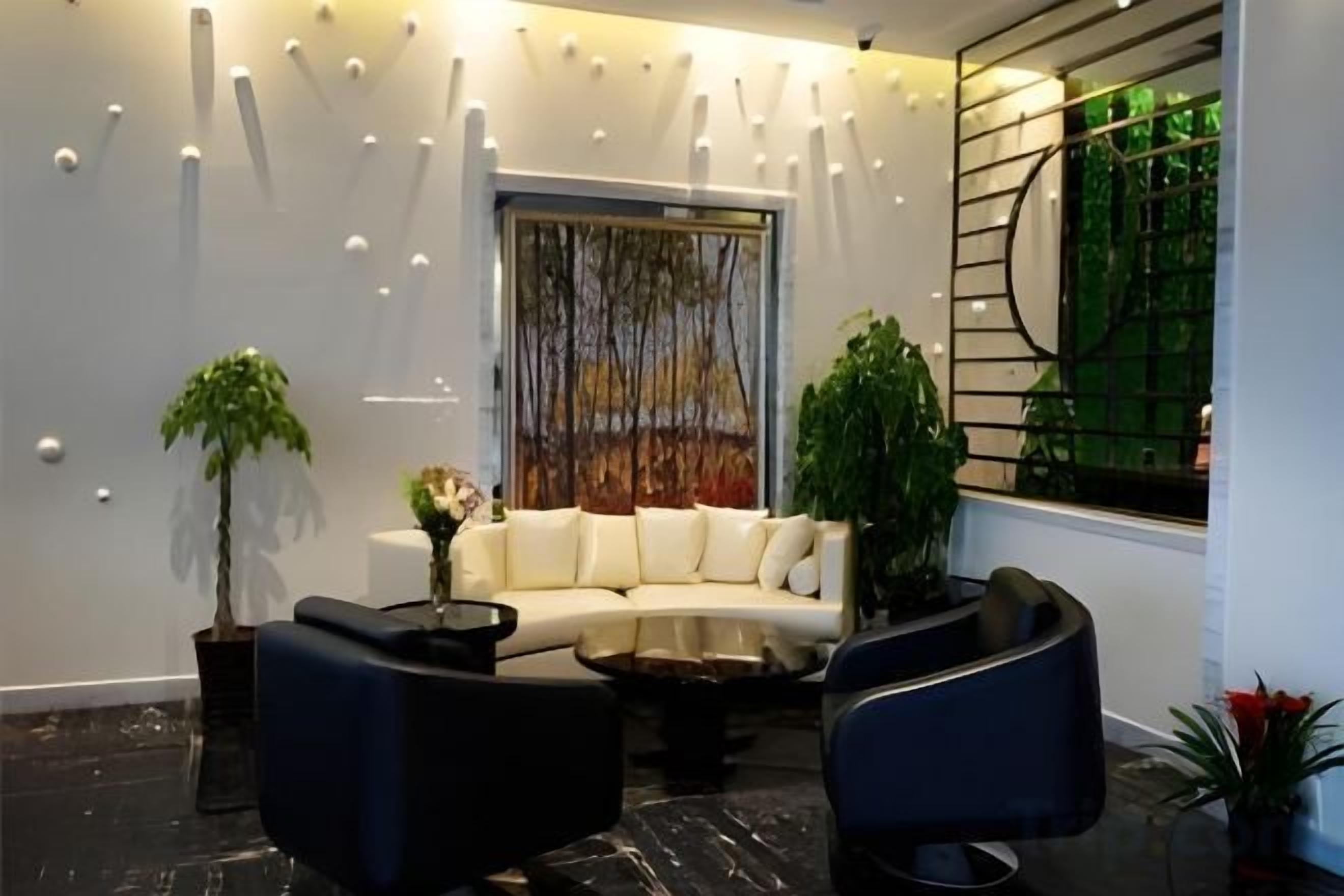 A modern living room with a white sofa, black armchairs, a coffee table, and decorative lighting.