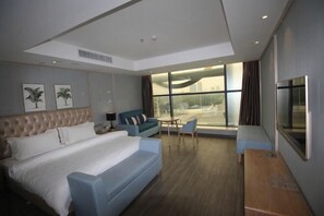 Una habitación de hotel moderna con una cama grande, un sofá, una mesita y un televisor.