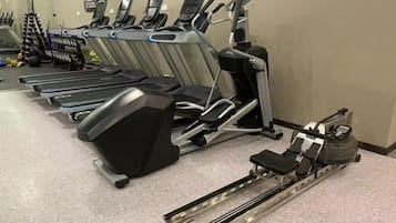 A row of treadmills in a gym with a stationary bike and a rowing machine.