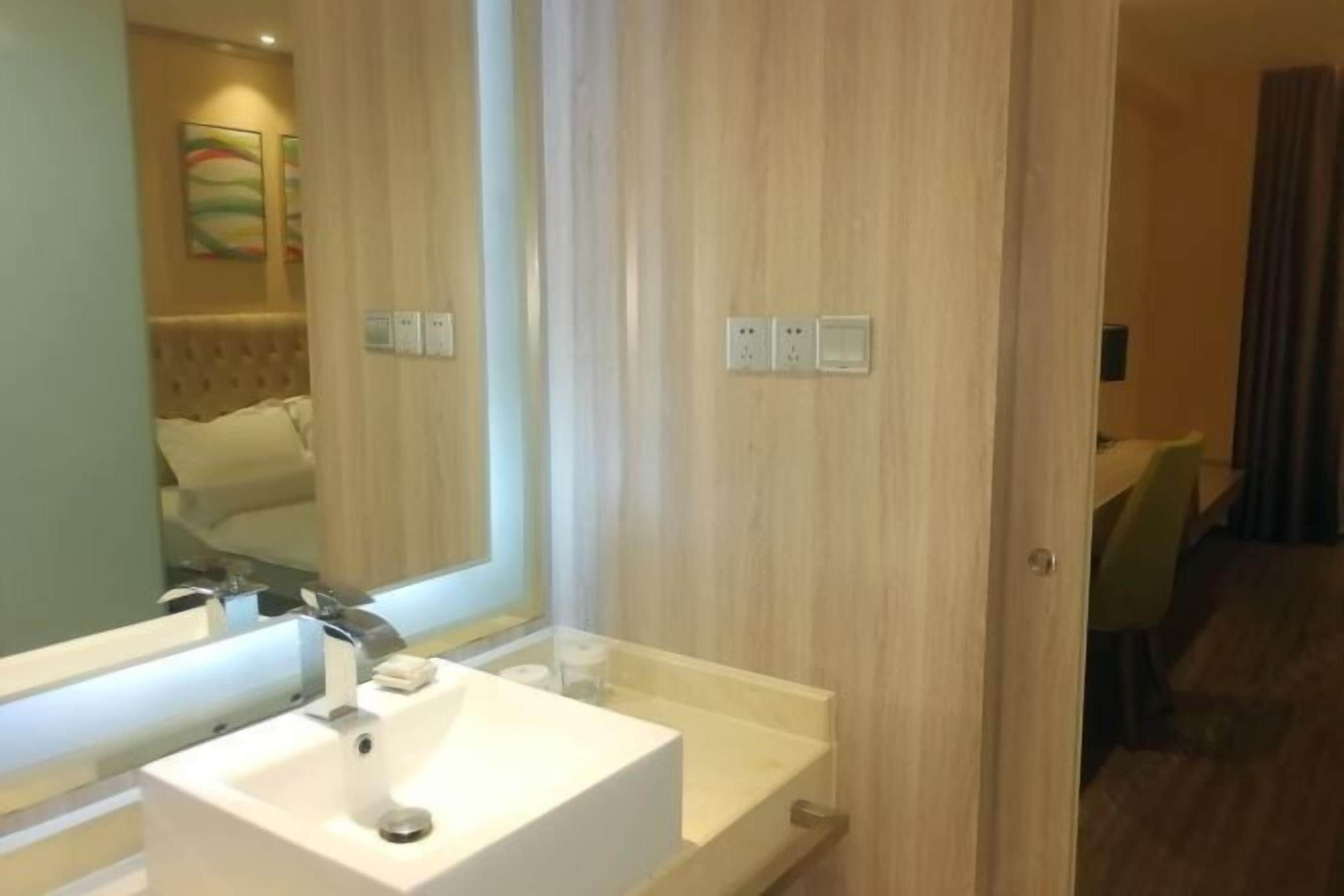 A modern bathroom with a white sink, mirror, and wooden paneling.