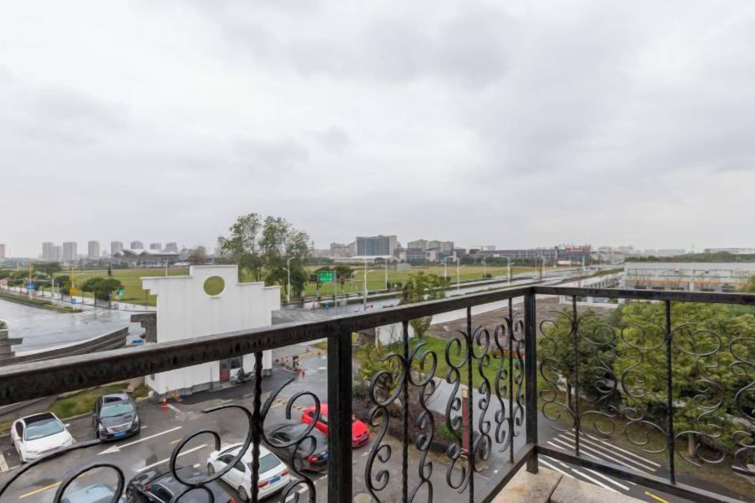 A balcony with a view of a cityscape, including buildings and a road with cars.