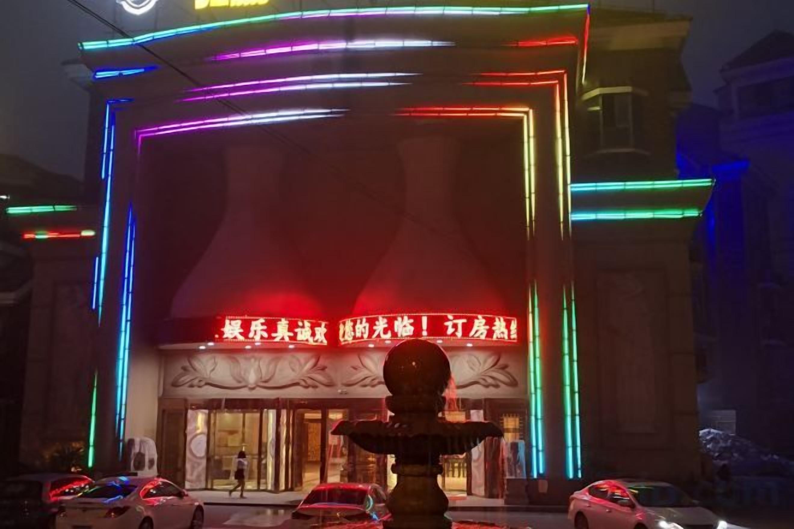 A hotel facade with illuminated neon lights and a prominent entrance.