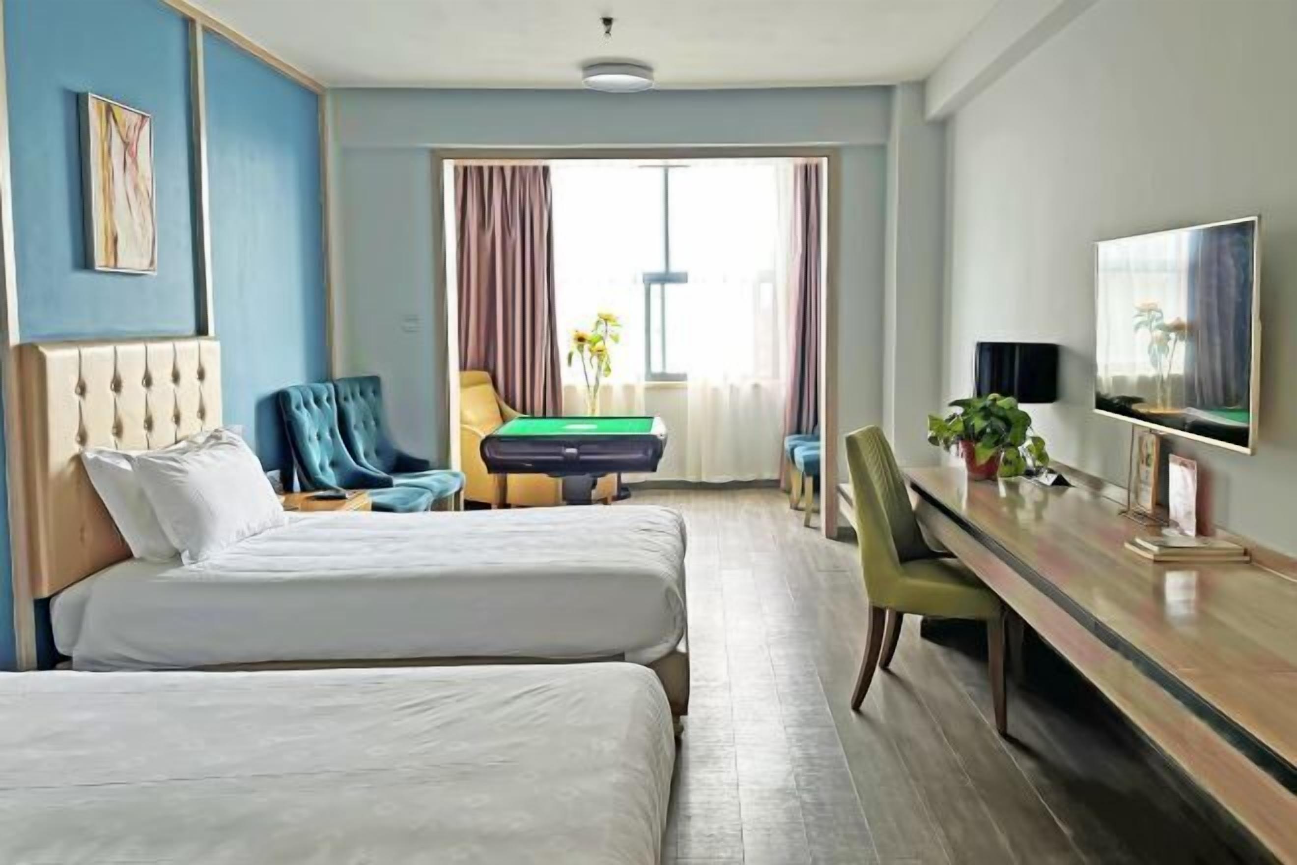 Een hotelkamer met twee bedden, een bureau met een televisie, een pooltafel en uitzicht op het landschap.