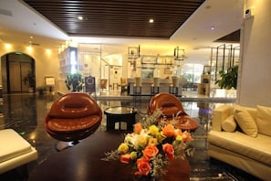 A lobby with leather chairs, a round table with a floral centerpiece, and a sofa. - Shanghai Jinshanzui Yucun Hotel (Shanghai)