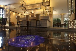 Zona de bar con piso reflectante, taburetes y mostrador.