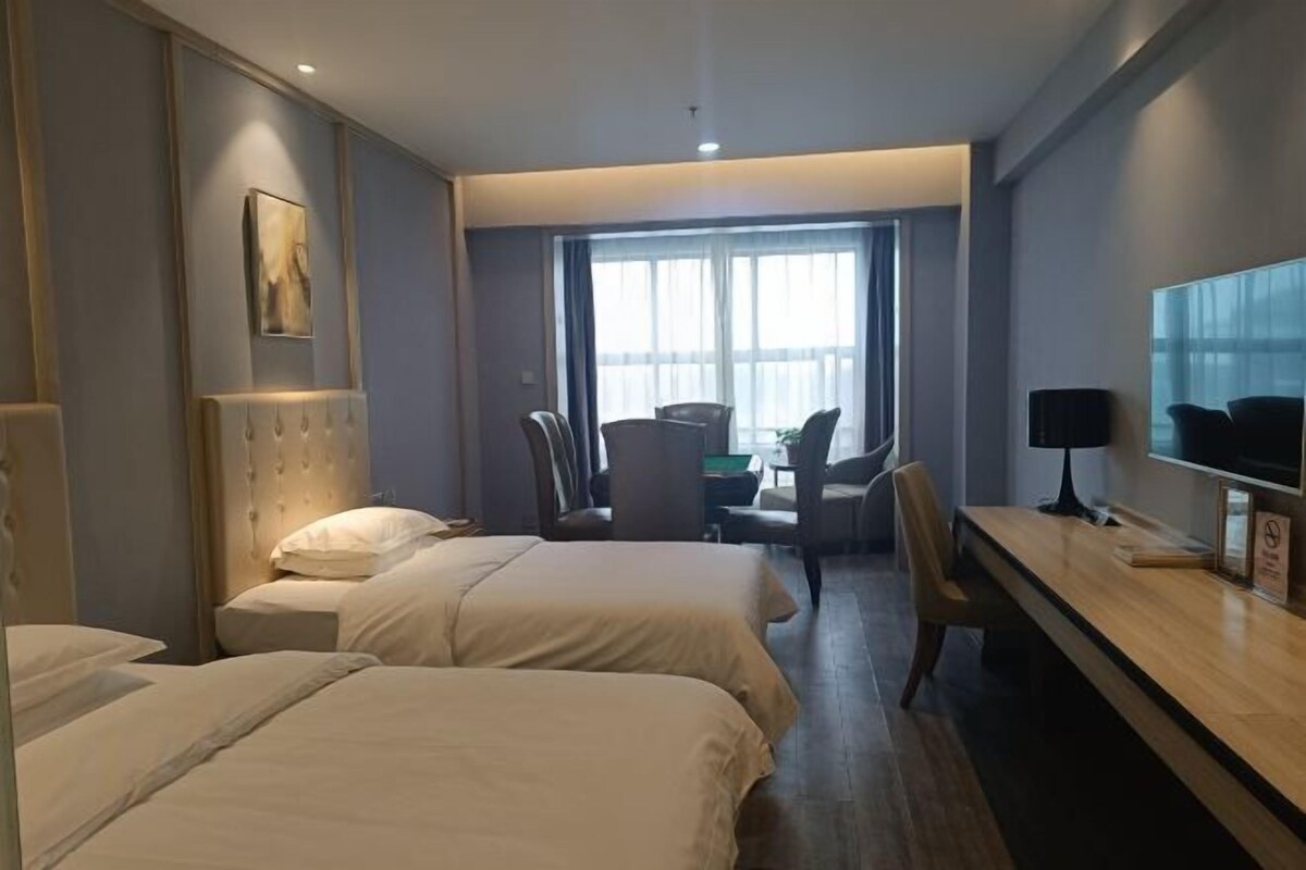 Hotellihuone, jossa on kaksi sänkyä, työpöytä, tuoli ja televisio.