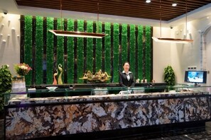 Una recepción con encimera de mármol, una pared vegetal vertical verde y una pantalla de televisión.