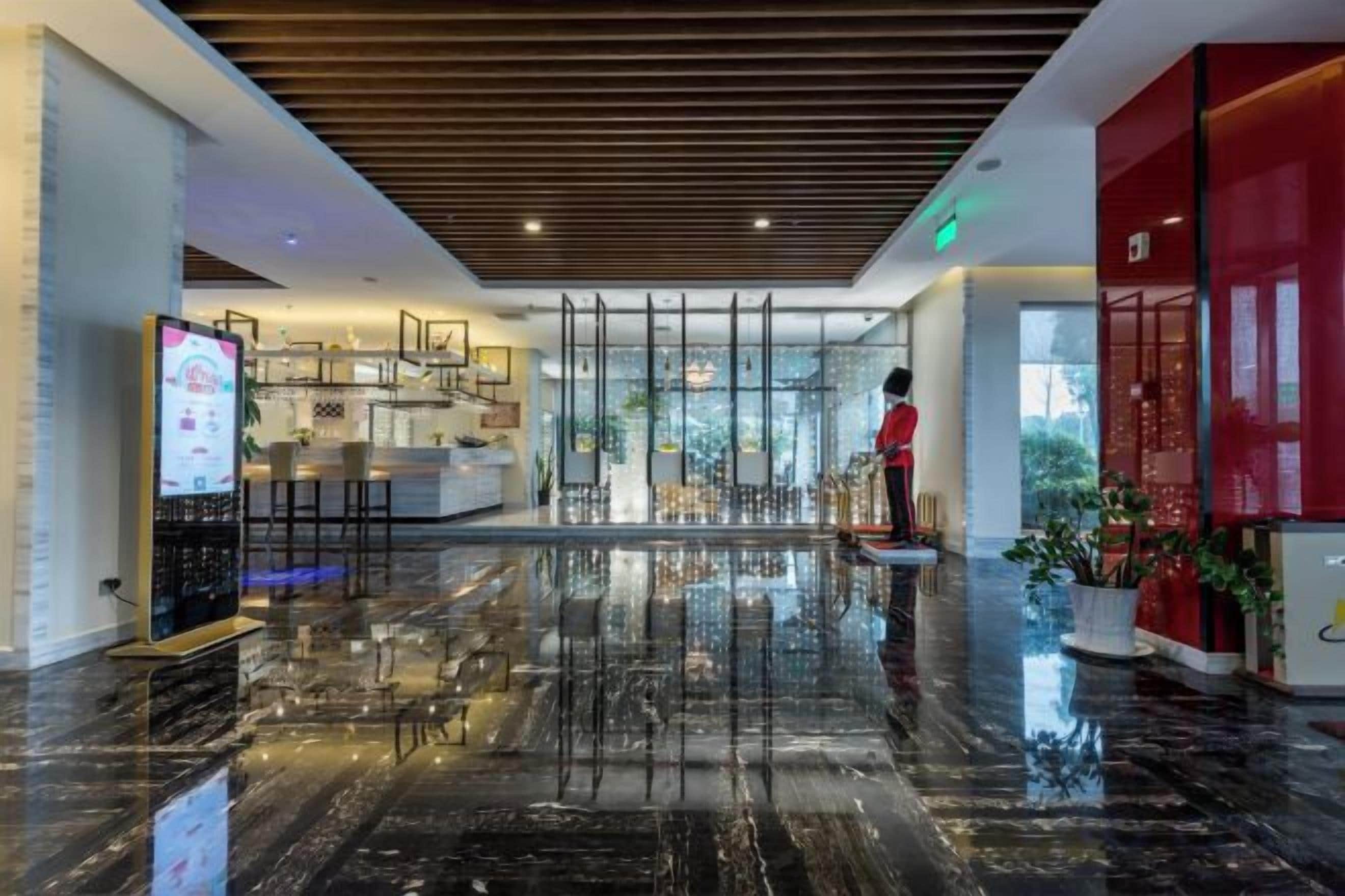 A hotel lobby with a polished marble floor, a reception desk, and a red accent wall.