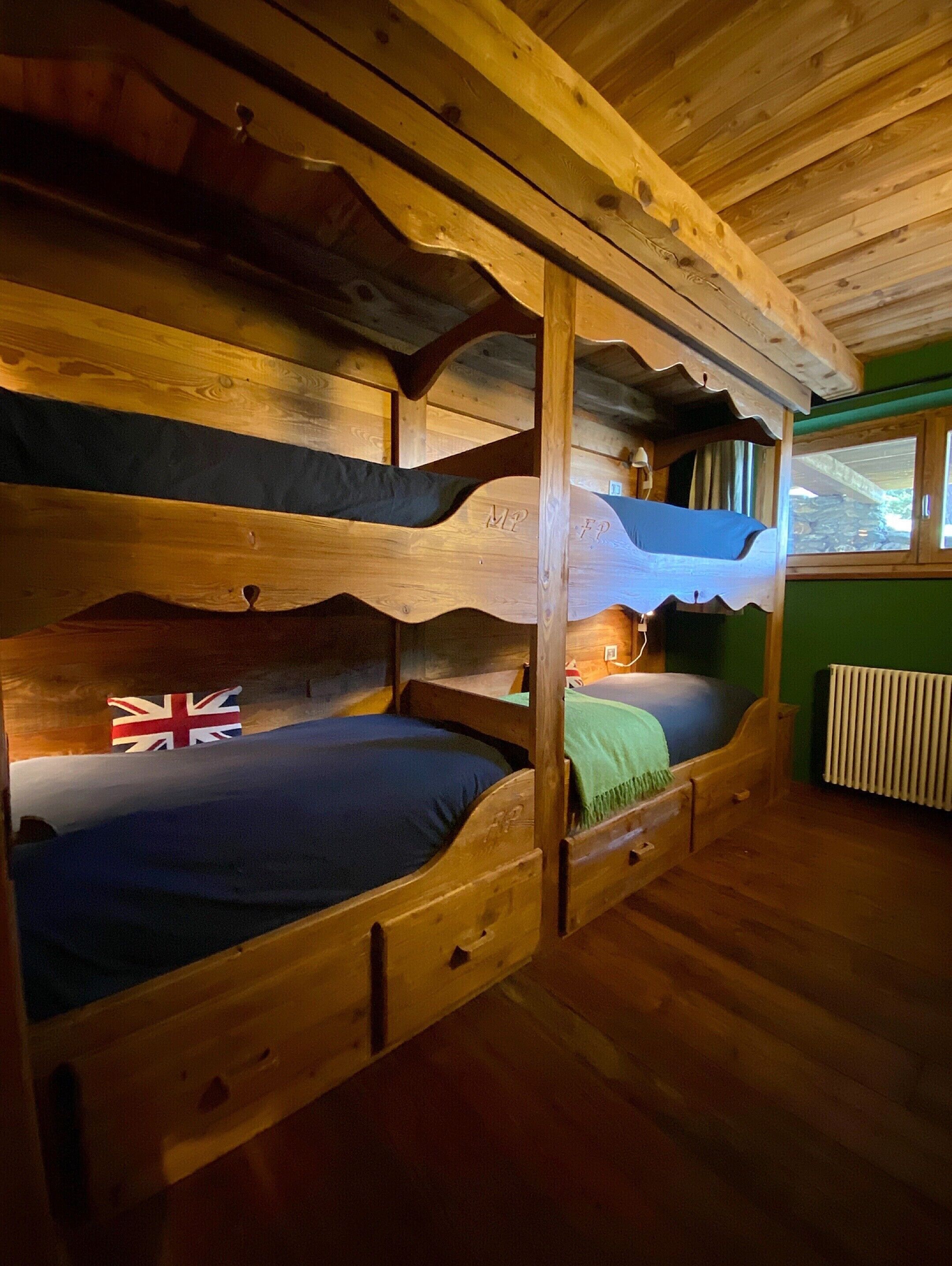 A bunk bed room with a flag, wooden beams, and a window.