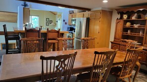 A dining area with a wooden table and chairs, a kitchen with wooden cabinets, and a visible refrigerator.