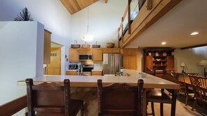 A spacious kitchen with wooden cabinets, a large island with bar stools, and a dining area with wooden chairs.