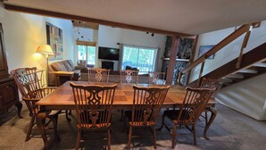 A dining area with a wooden table and chairs, a sofa, a TV, and a staircase. - Snowcreek Resort Vacation Rental 644 (Mammoth Lakes)