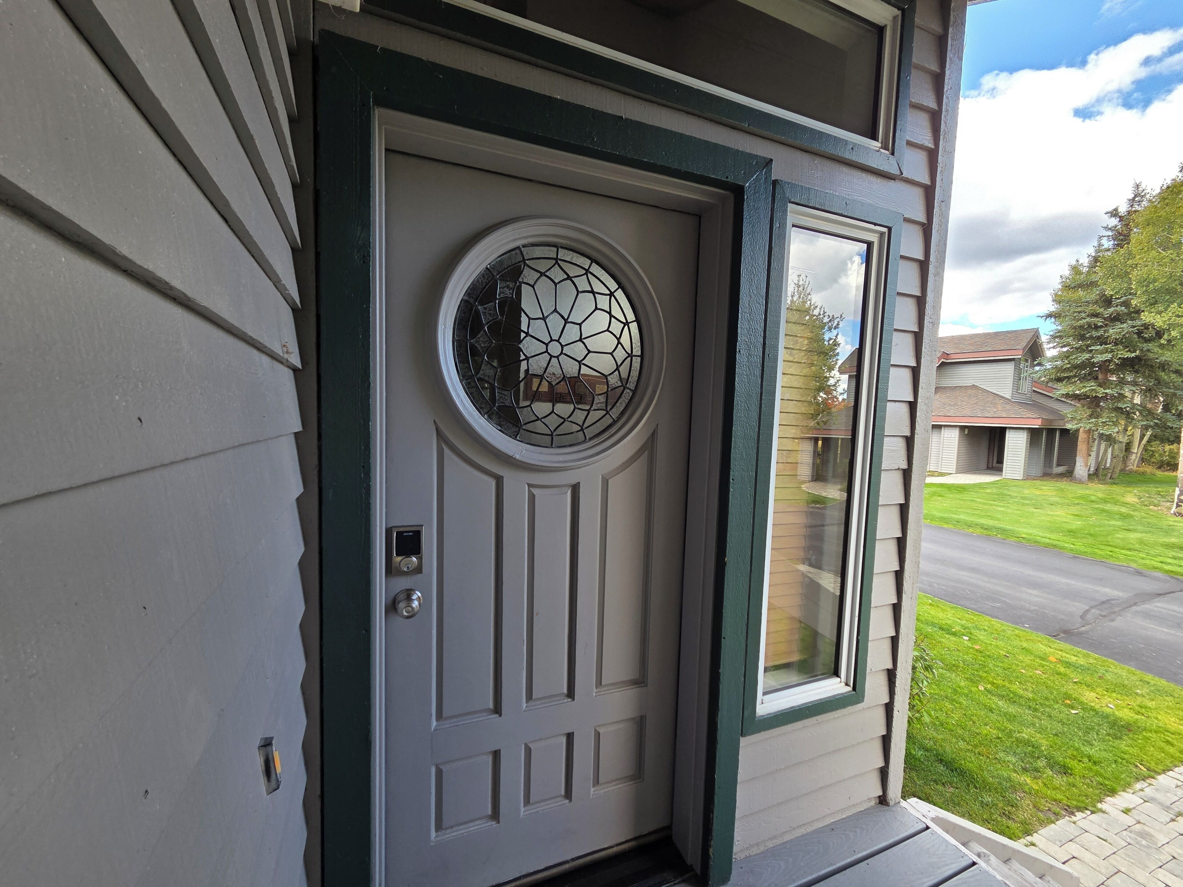 A residential entryway with a white door, a glass window, and a green door frame.