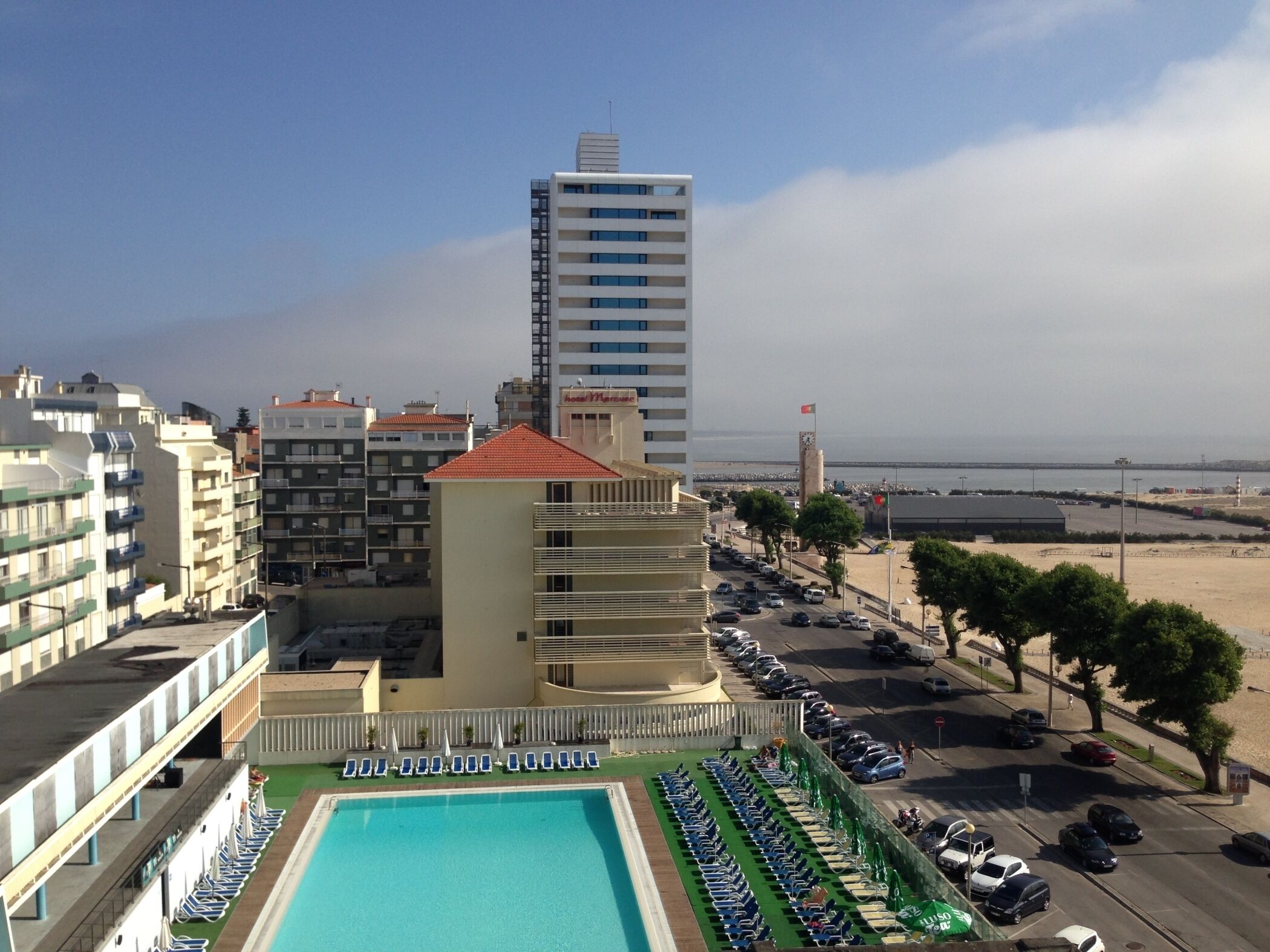 Un hotel con piscina, varios pisos y vistas a la playa y al mar.