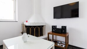 Un salon moderne avec une cheminée blanche, un téléviseur à écran plat fixé au mur et une table basse avec un plateau en verre.
