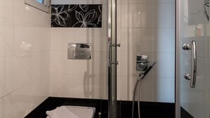 Une salle de bain dotée d’une douche à parois de verre, de toilettes et d’un bidet.