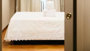 A hotel room with a bed, a white towel, and a large window with curtains. - Residenza Ognissanti  (Florence)