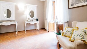 A living room with a sofa, two white side tables, a mirror, and a radiator. - Residenza Ognissanti  (Florence)
