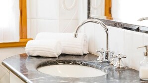 A bathroom with a marble sink, a large mirror, and a towel rack with folded towels. - Residenza Ognissanti  (Florence)