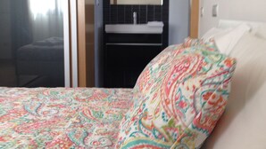 A hotel room with a bed, a bathroom with a sink, and a mirror. - Figueira Duplex Praia Buarcos, wi-fi, cable Tv (Figueira da Foz)
