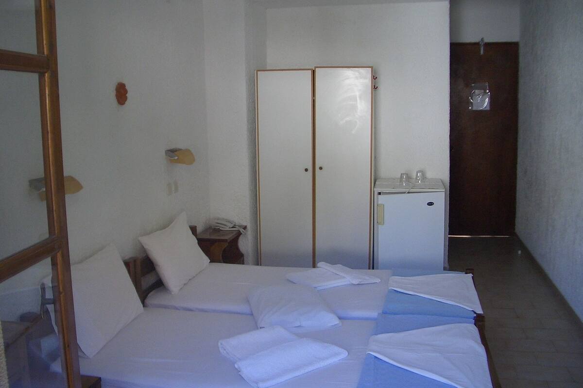 A hotel room with a bed, a desk, a wardrobe, and a door.