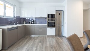 A modern kitchen with white cabinets, a built-in oven, and a stainless steel refrigerator.