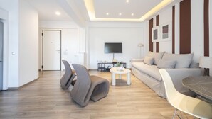 A modern living room with a sofa, chairs, a coffee table, and a TV.