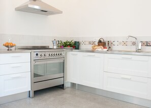 Cozinha moderna com armários brancos, fogão de aço inoxidável e painel de azulejos.