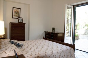 A bedroom with a bed, dresser, desk, and a window with a view of the outdoors.
