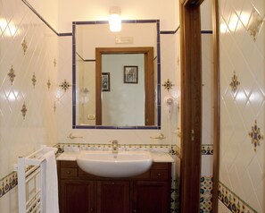 A bathroom with a white sink, wooden cabinets, and a mirror above the sink.