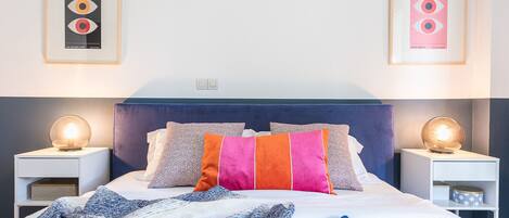 A neatly arranged bedroom with a bed, pillows, and bedside tables.