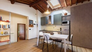 A modern kitchen with white cabinetry, a dining table with chairs, and a wooden floor. - Apartment Cappelle Medicee Florence by Mmega (Firenze)