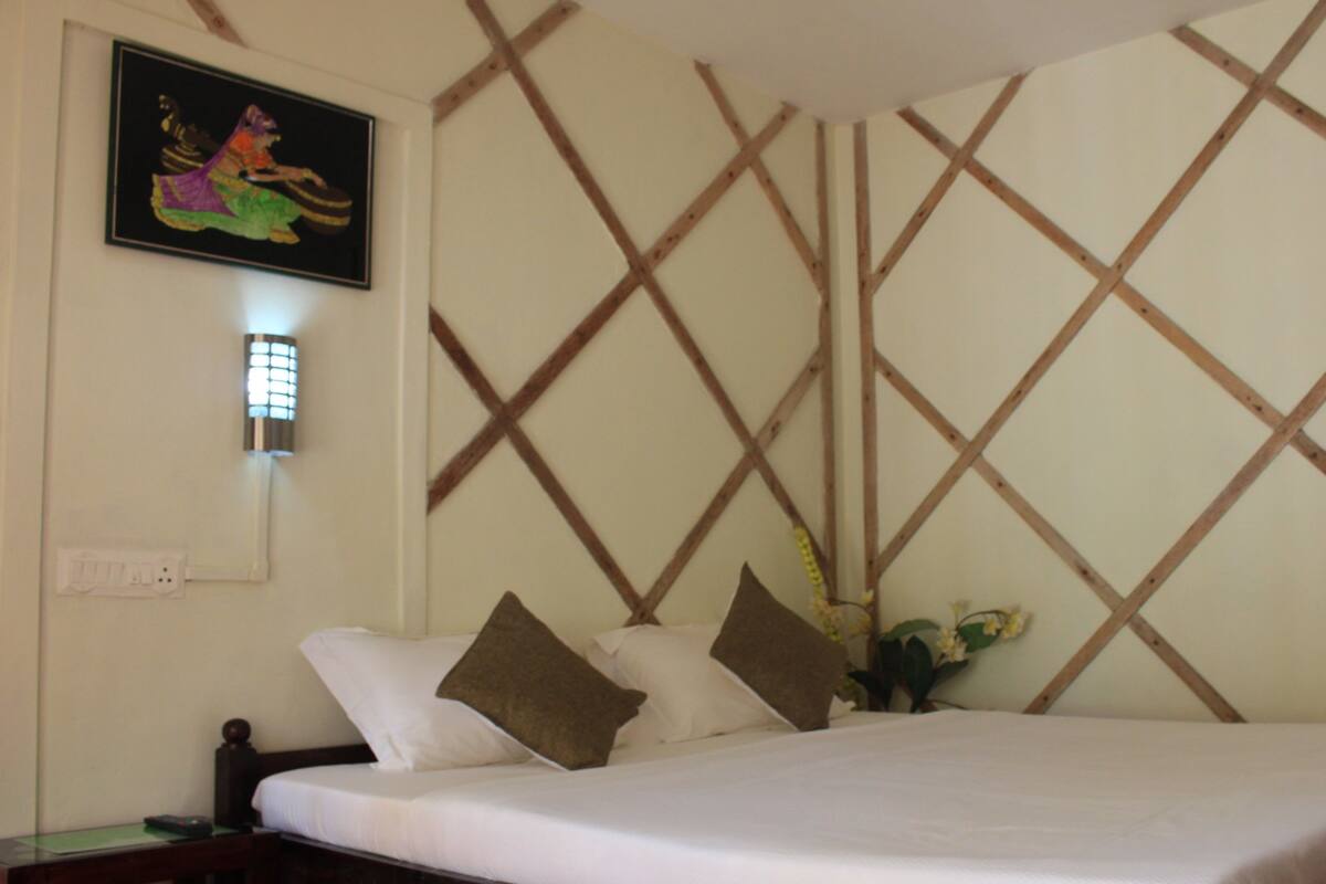 Ein Hotelzimmer mit einem Bett, einem Nachttisch, einer Wandleuchte und einem gerahmten Bild.