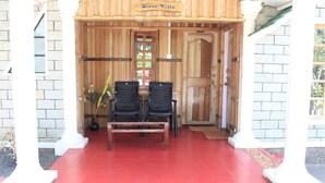 Una entrada de madera con un cartel que dice "Stone Villa", dos sillas negras, un banco de madera y un suelo de baldosas rojas.