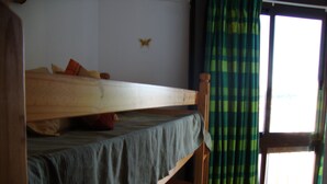 Een slaapkamer met een stapelbed, raam en gordijnen.
