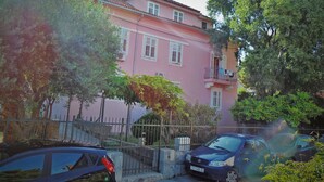 A pink building with a balcony, surrounded by trees and a metal fence. - Studios Ani (Split)