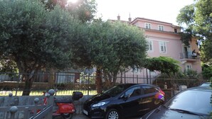 A pink building with a balcony, a parked scooter, and a black car. - Studios Ani (Split)