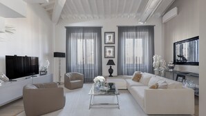A modern living room with a sofa, armchair, and coffee table. There is a television, a lamp, and a fireplace.