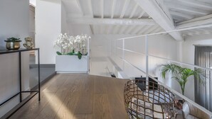 A spacious room with a wooden floor, a white ceiling, and a staircase leading to an upper level.
