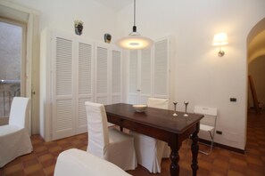 A dining area with a wooden table, white chairs, and a hanging light fixture.